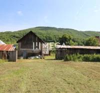 A family house in Nižná Jablonka with wooden buildings and surrounding green landscape.