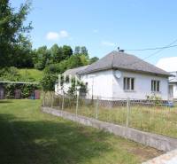 A family house in Nižná Jablonka with a fenced garden, surrounded by trees and a lawn.