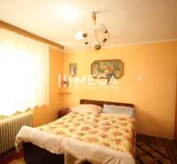 Bedroom in a family house with a bed, paintings, and yellow walls.