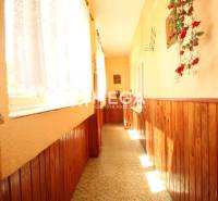 A hallway in a family house with wooden paneling and a window with a curtain.