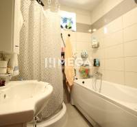A bathroom in a 3-room apartment with a bathtub, a sink, and a shower screen.