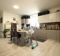 A kitchen in a 3-room apartment with wooden flooring, light furniture, and a dining table.