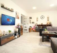 Living room in a 3-room apartment with a television, gray sofa, and wooden elements.