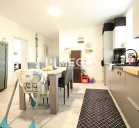 The kitchen in a 3-room apartment with a dining table, a child's chair, and a cabinet.