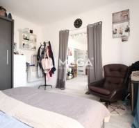 A bedroom in a 3-room apartment with a comfortable armchair, bed, and storage space.