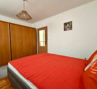 Bedroom with a wooden wardrobe, red bed, and ceiling light in a family house.