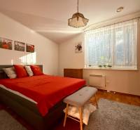 Bedroom in a family house with a red bed, wardrobe, and large window.