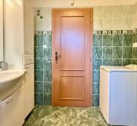 Bathroom with a washing machine, sink, and tiles in a family house.