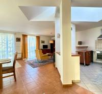 Interior of a family house with a kitchen, dining table, and living area with glass doors.