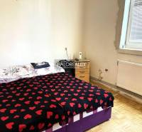 A bedroom in a family house with a bed and a nightstand, there are candles on the table.