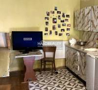 A kitchen in a family house with a television, photos on the wall, and a stove.