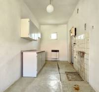 A kitchen with white cabinets, a stove, and a small window in the Living - Residential area.