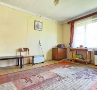 A room with carpets, older furniture, and windows, cracks on the walls. Properties - living.