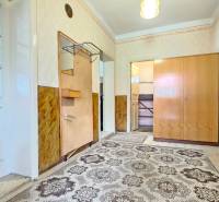 Entrance hallway with a cabinet, carpet, and wooden paneling in the living space.