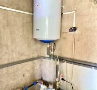 Boiler on the wall and pump in the corner in a family house.