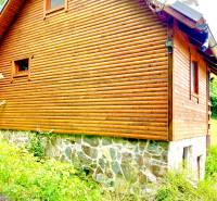A wooden family house in Štefultov with a stone foundation surrounded by greenery.
