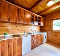 A wooden kitchen in a family house with wooden cabinets and a view from the window.