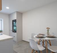 A kitchen in a studio apartment with modern equipment and a small dining table.