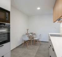 A kitchen in a studio apartment with a table, chairs, and a built-in oven.