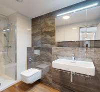 A bathroom with a shower, sink, and mirror in a 4-room apartment.