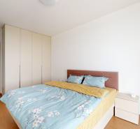 Bedroom in a 4-room apartment with a bed, wardrobe, and white walls.