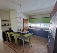 A kitchen in a family house with a dining table and green details.