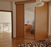 Interior of a family house with a built-in wardrobe, a mirror, and leopard patterns on the bed.