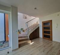 A bright hallway with a wooden staircase and railing in a family house.