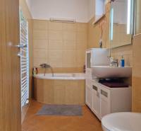 A bathroom in a family house with a corner bathtub, cabinet, sink, and toilet.