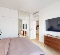 A bedroom with a large TV, mirrored wardrobes, and a plant in a three-room apartment.