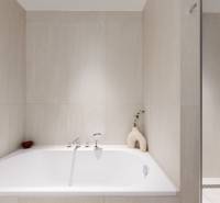 Bathroom with a shower and a bathtub in a 3-room apartment, elegant light tiles.