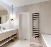 A bathroom with a large mirror, a bathtub, and a white sink in a 3-room apartment.