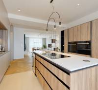 A stylish kitchen with an island, wooden surfaces, and built-in appliances in a 3-room apartment.