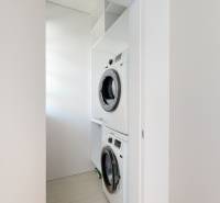 A washing machine and dryer in the white interior of a 3-room apartment.