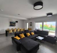 Living room in a 4-room apartment with a large sofa, dining table, and a view of the terrace.