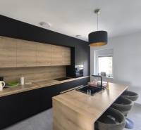 A kitchen in a 4-room apartment with wooden and black furniture and bar stools.