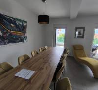Dining room in a 4-room apartment with a long table, paintings, and a comfortable armchair.