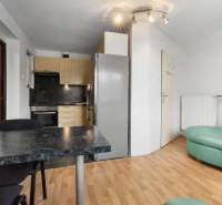 A kitchen in a family house with a dining table, a green sofa, and a wooden floor.