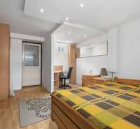 Bedroom in a family house with a wooden bed, desk, and wardrobes.