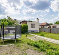 The garden of a family house on Mokráň Záhon in Bratislava-Ružinov with a trampoline and a fence.