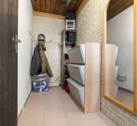 A narrow hallway with a coat rack, mirror, and storage space in a family house.