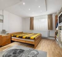 Bright bedroom with wooden flooring, bed, dresser, and carpet in a family house.