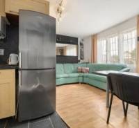 A kitchen with a refrigerator and a dining area next to the living room in a family house.