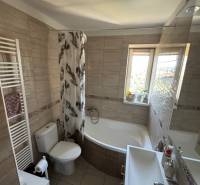 A bathroom in a 3-room apartment with a bathtub, a sink, and a window for natural light.