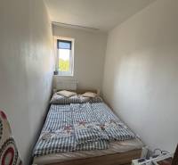 A small bedroom with a bed in a three-room apartment, simple furnishings and a white interior.