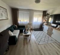 Living room in a three-room apartment with a sofa, table, television, and carpeted floor.