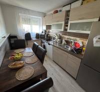 A kitchen in a 3-room apartment with a table, chairs, and modern equipment in pleasant lighting.
