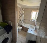 Bathroom with a washing machine, bathtub, and sink in a 3-room apartment.
