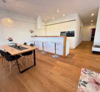 Dining area with a wooden table and a kitchen bar counter in a 4-room apartment.