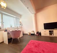 A room in a 4-room apartment with a desk, a television, and a pink carpet.